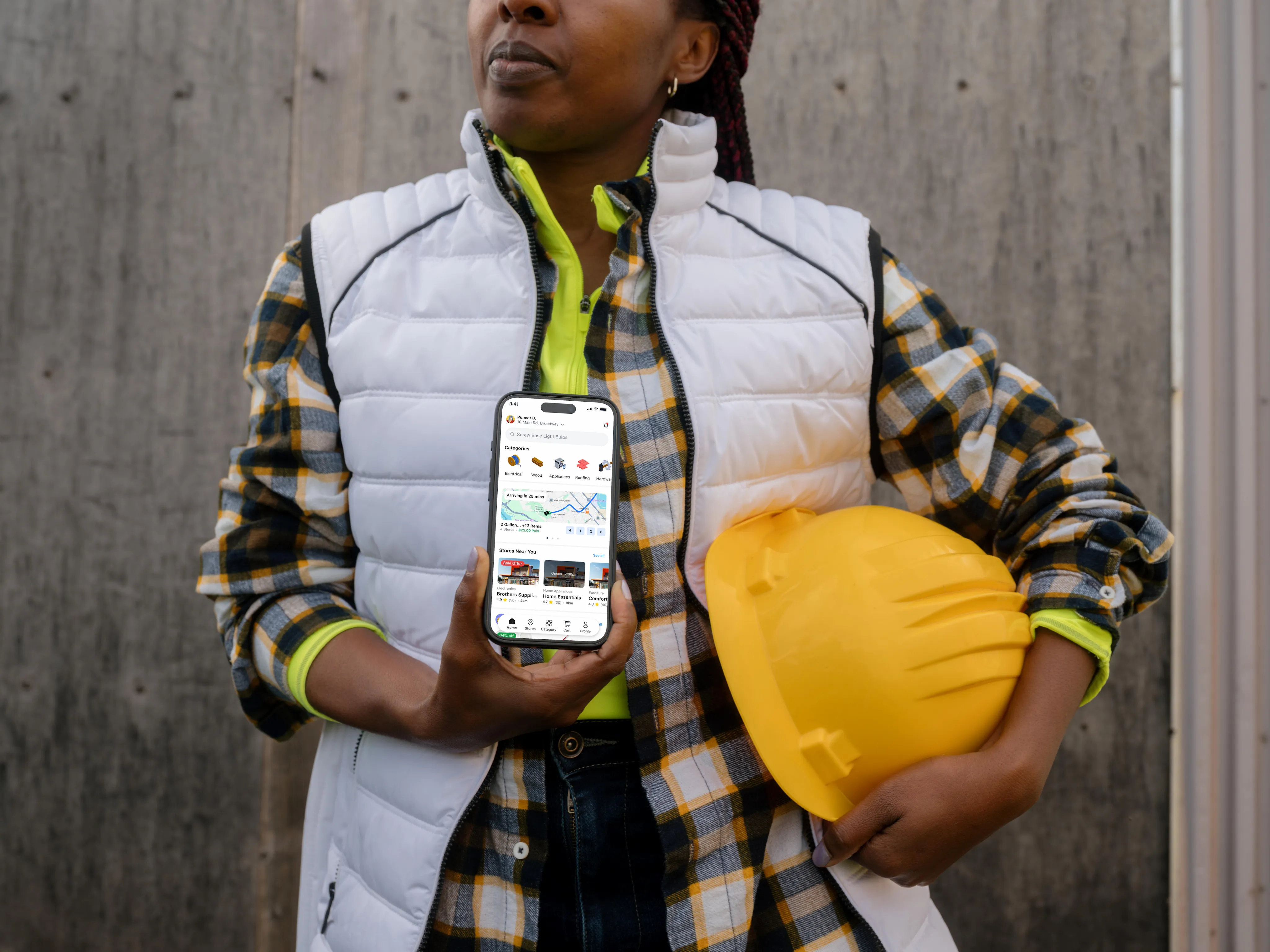 A contractor holding a hard hat and a phone showing the InstaSupply app